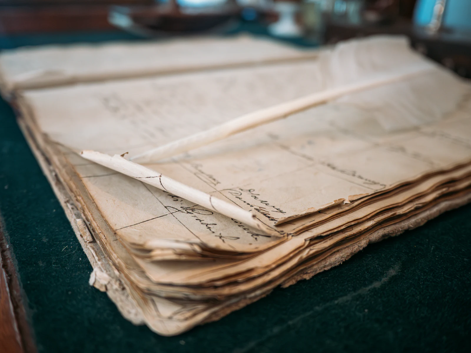 A worn handwritten ledger with ruled columns and a quill pen