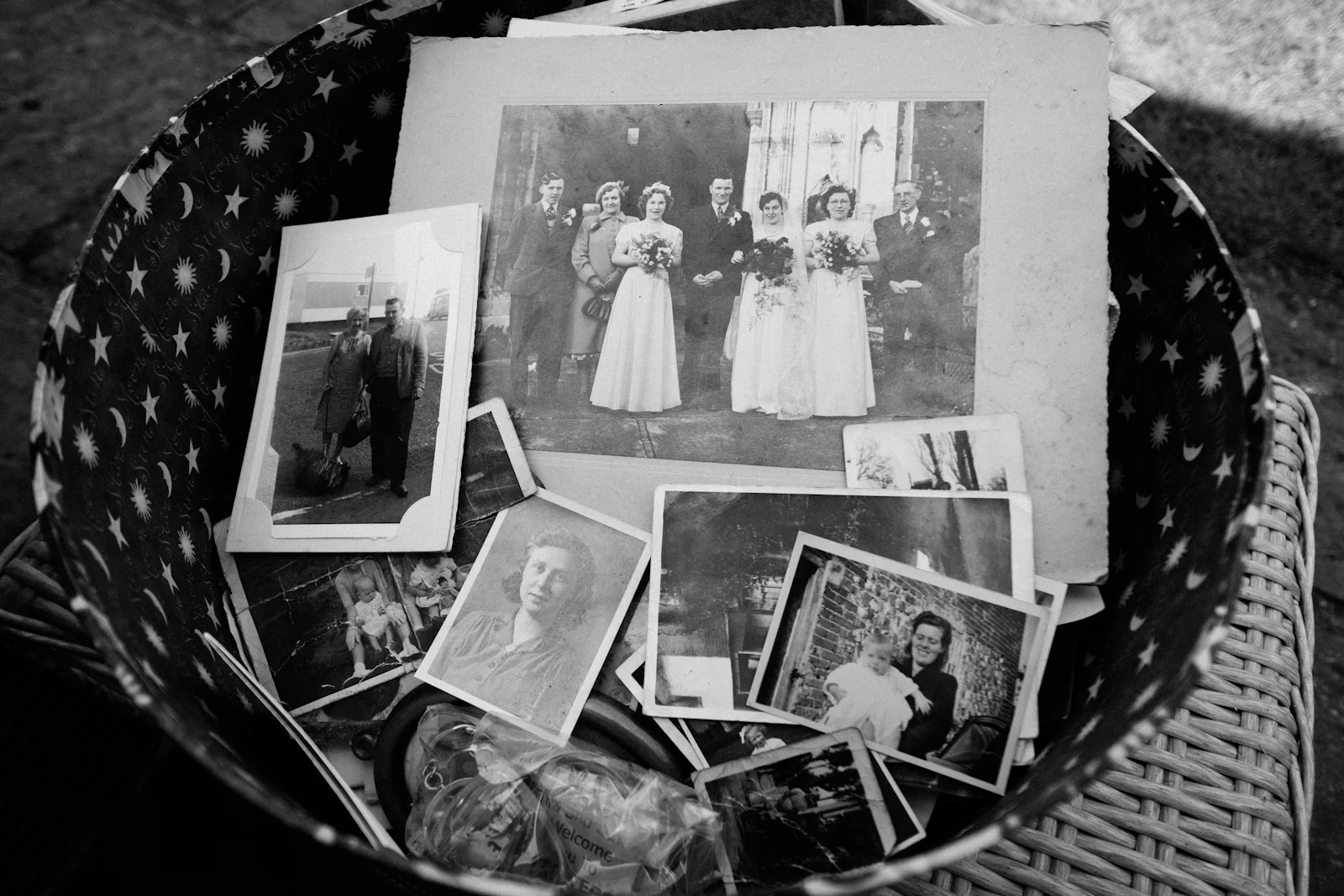 A basket of old black-and-white family photographs, including a wedding group
